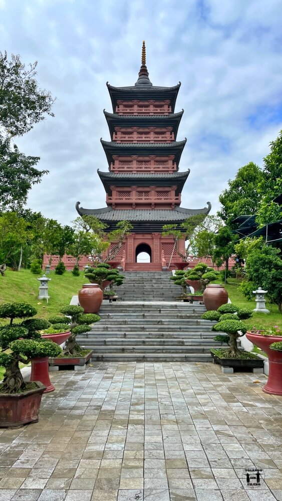 Pagoda del templo vista desde lejos con escaleras y árboles a los lados 
